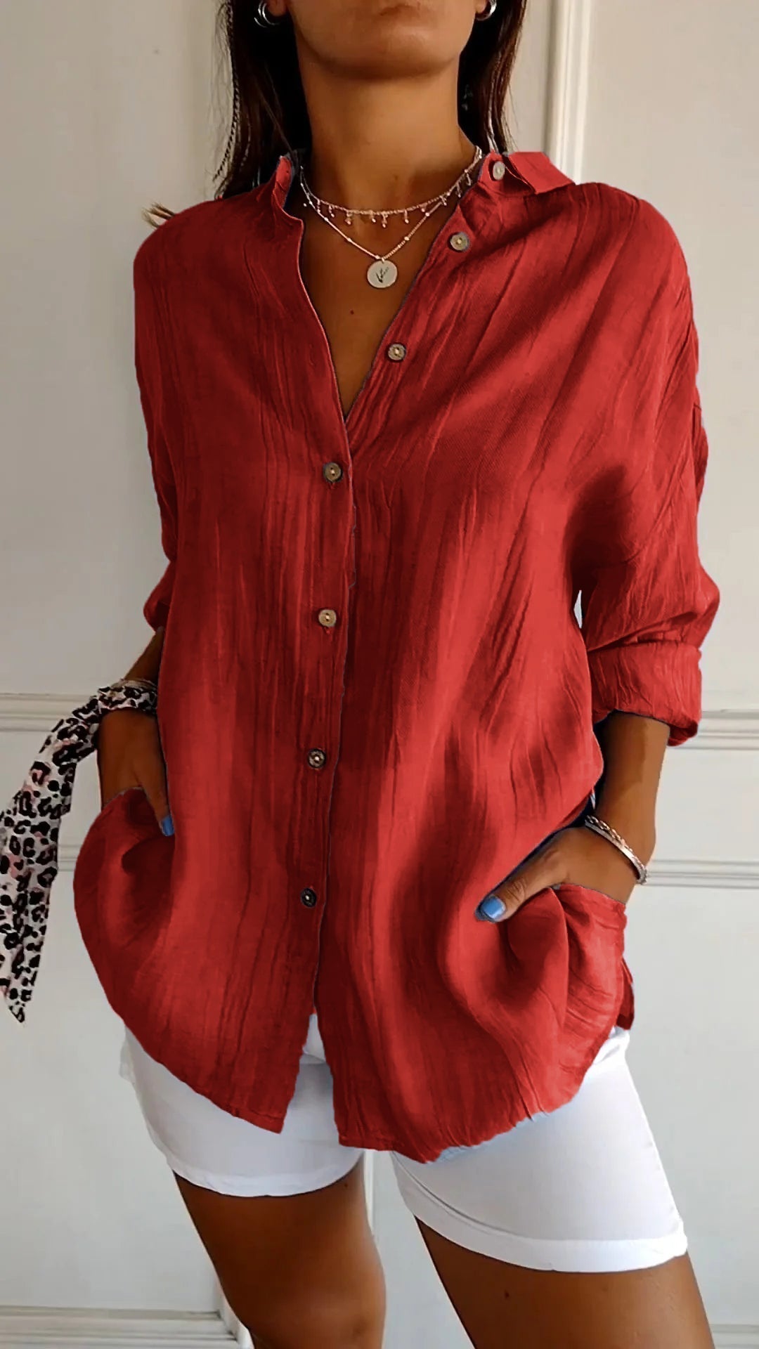 Camicia rossa in lino con bottoni, maniche lunghe e tasche, indossata con pantaloni bianchi. Stile casual elegante, moda donna.