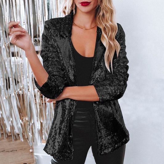 Donna in giacca di paillettes nere, top nero e pantaloni in pelle, posa elegante. Moda glamour, abbigliamento da sera, stile sofisticato.