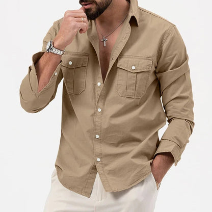 Camicia beige da uomo con maniche lunghe, tasche frontali e bottoni bianchi, indossata con pantaloni chiari. Stile casual elegante.