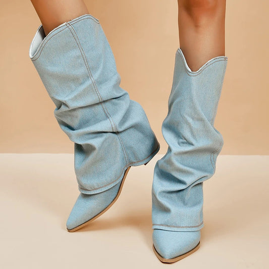 Stivali denim azzurri a punta, design slouchy, tacco basso, su sfondo beige. Scarpe moda donna, stile casual chic, tendenza autunno inverno.