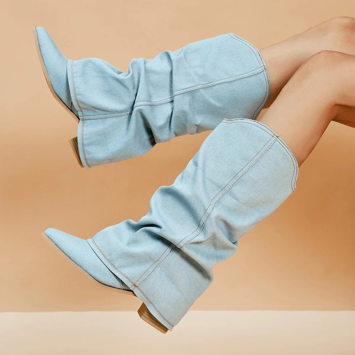 Stivali alti in denim chiaro, design moderno, su sfondo beige. Calzature moda donna, tendenza autunno, stile casual chic.