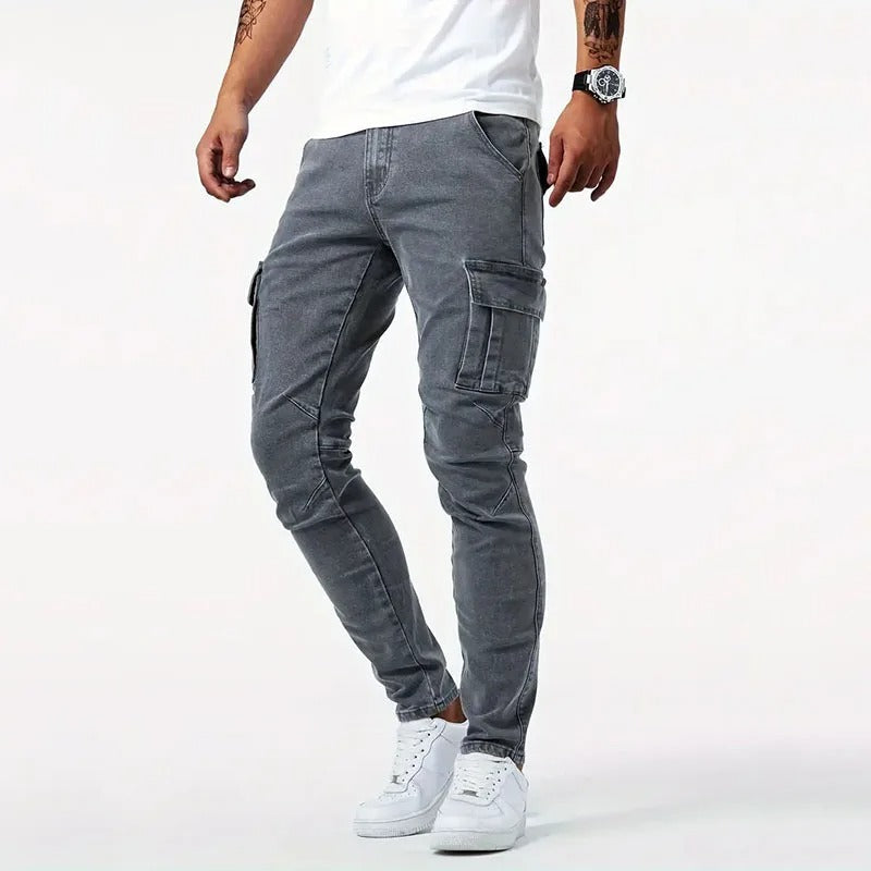Jeans cargo grigi da uomo, vestibilità slim, con tasche laterali, abbinati a scarpe da ginnastica bianche e t-shirt bianca. Moda casual maschile.