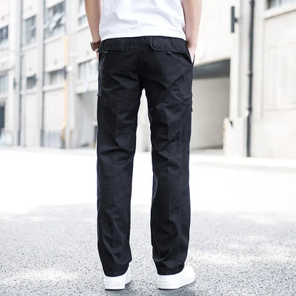 Pantaloni cargo neri da uomo, stile casual, indossati con scarpe bianche, sfondo urbano. Moda maschile, abbigliamento streetwear.