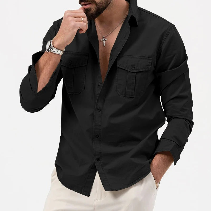 Camicia nera da uomo con maniche lunghe, colletto classico e tasche frontali, abbinata a pantaloni chiari. Stile elegante e moderno.