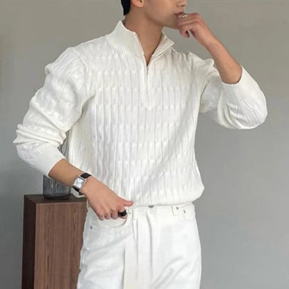 Uomo in maglione bianco a collo alto, design a trecce, posa pensierosa. Moda maschile elegante, abbigliamento invernale, stile casual chic.