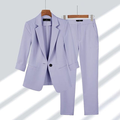Completo donna elegante color lavanda, giacca e pantaloni abbinati, appesi su grucce di legno. Moda femminile, abbigliamento formale.