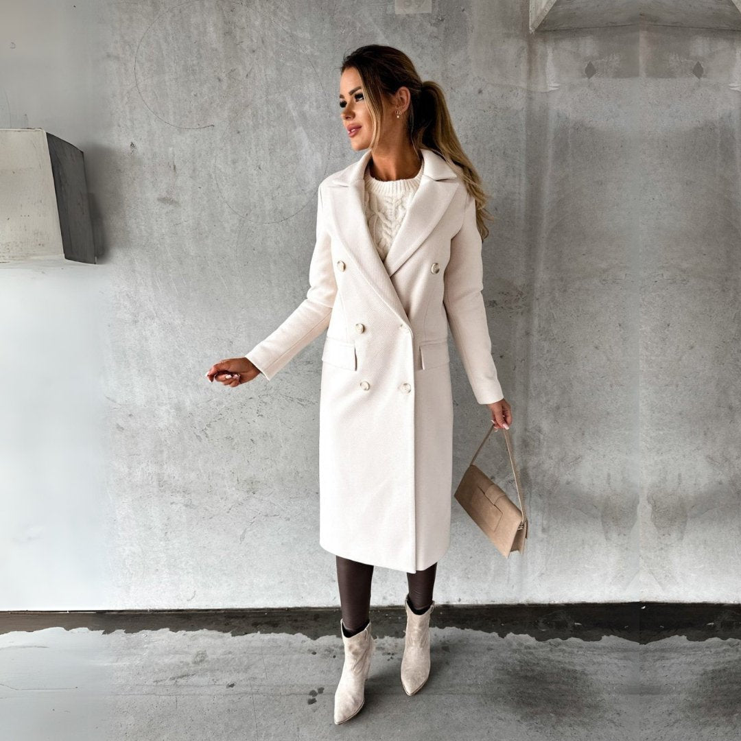 Donna con cappotto bianco elegante, borsa beige e stivali, posa su sfondo grigio. Moda autunnale, stile chic, abbigliamento invernale.