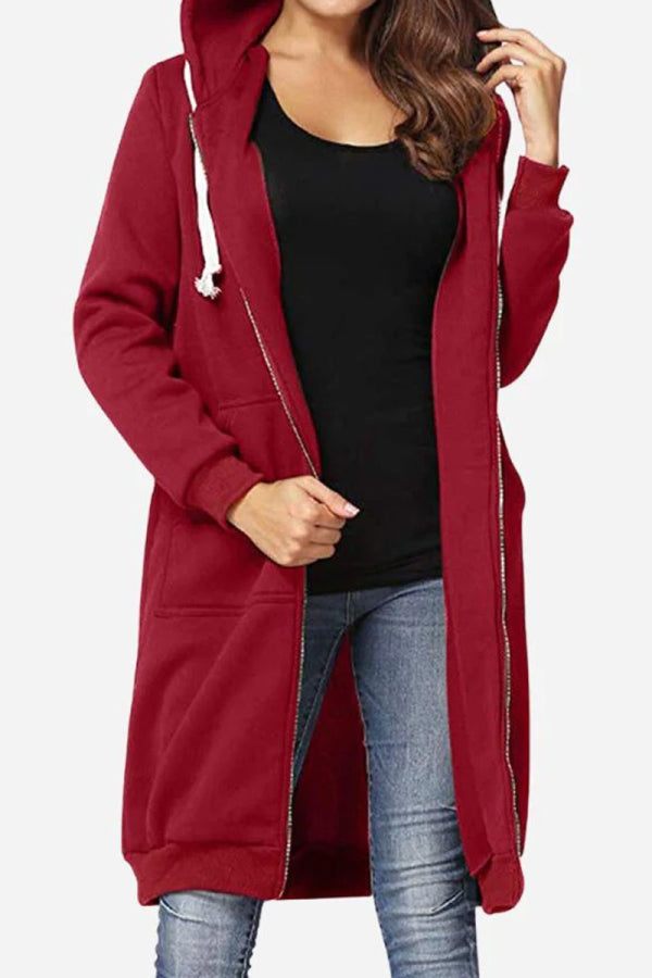 Donna con cappotto lungo rosso con cappuccio, zip e tasche, indossa jeans e maglietta nera. Moda casual autunnale, abbigliamento femminile trendy.