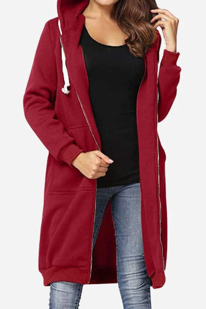 Donna con cappotto lungo rosso con cappuccio, zip e tasche, indossa jeans e maglietta nera. Moda casual autunnale, abbigliamento femminile trendy.