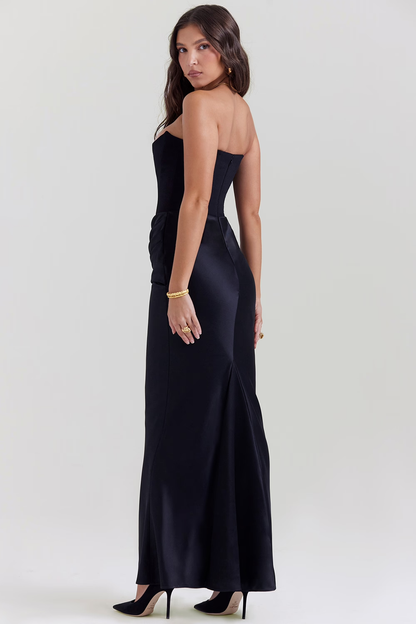 Donna in abito lungo nero elegante, senza spalline, con scarpe col tacco. Moda serale, abbigliamento formale, stile sofisticato.