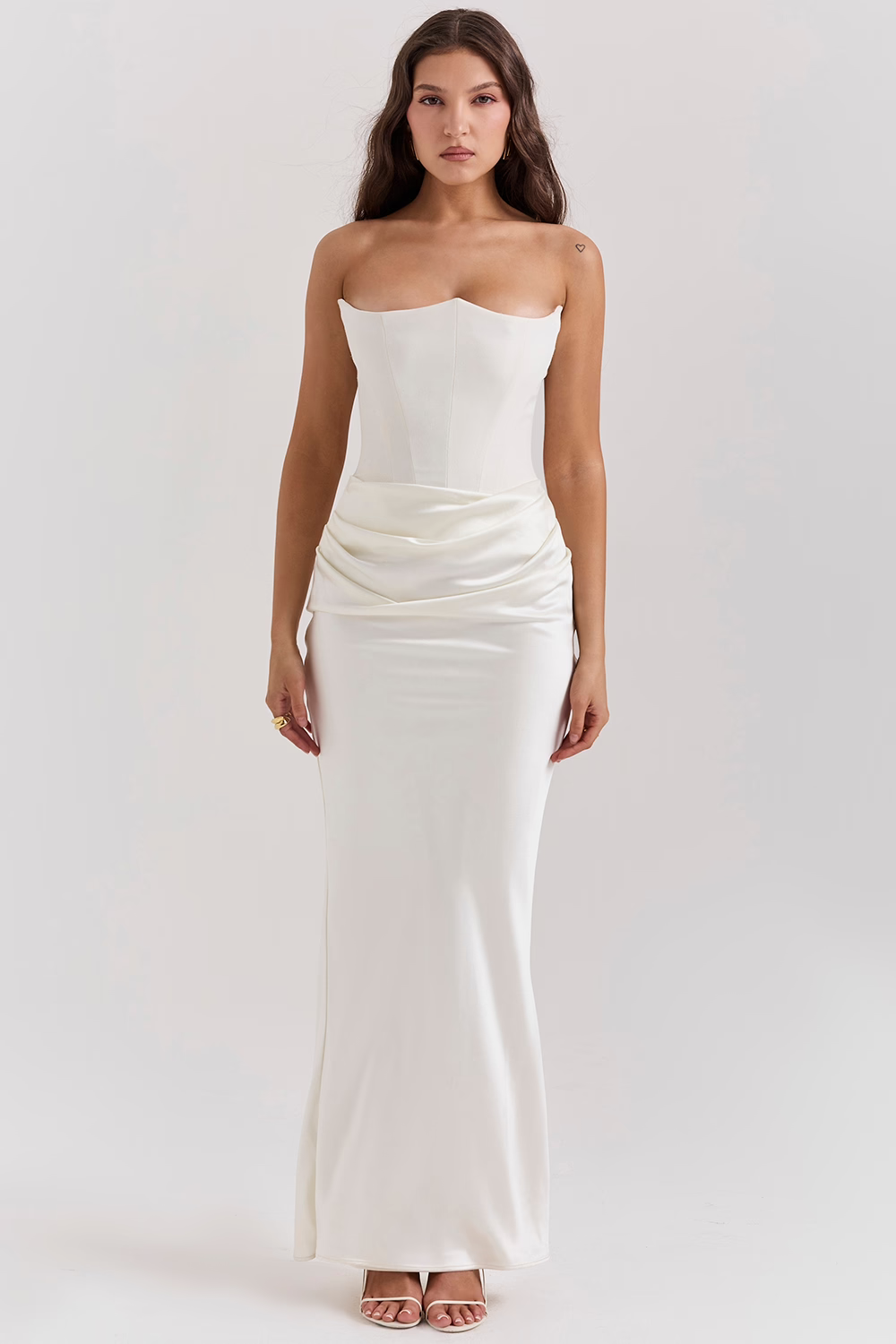 Donna in abito da sera bianco lungo, senza spalline, con drappeggio in vita. Elegante vestito da cerimonia, moda femminile, stile sofisticato.