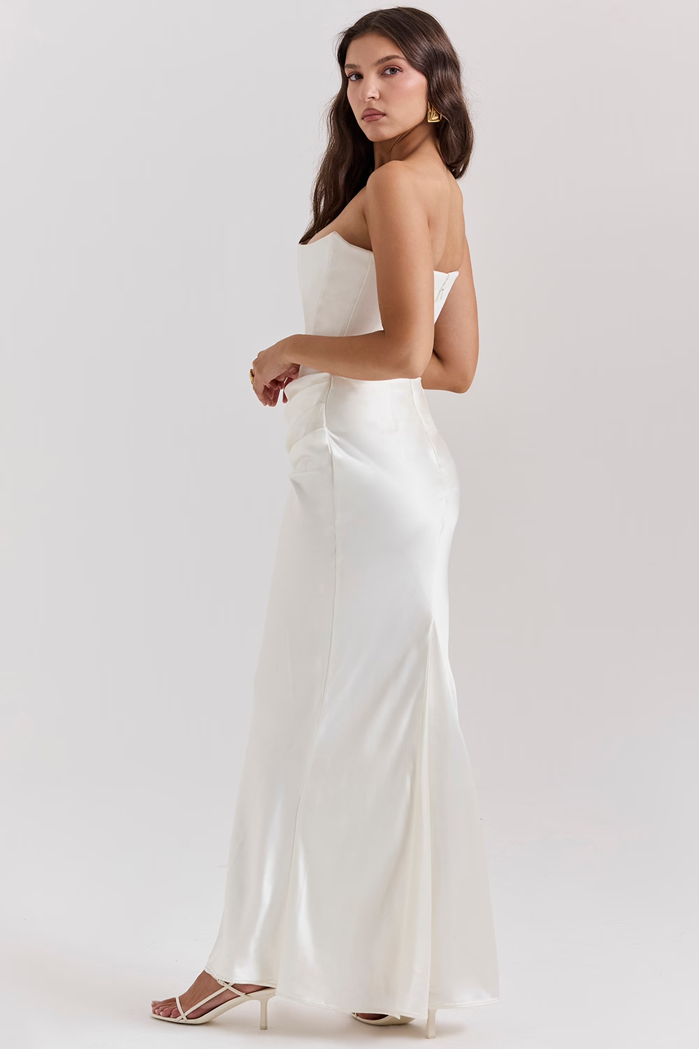 Donna in abito da sera bianco elegante, lungo e senza spalline, con sandali bianchi. Moda femminile, abbigliamento da cerimonia, stile sofisticato.