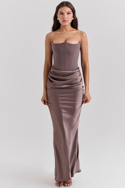 Donna in abito da sera lungo color taupe, senza spalline, con drappeggio elegante. Moda femminile, abbigliamento elegante, stile sofisticato.