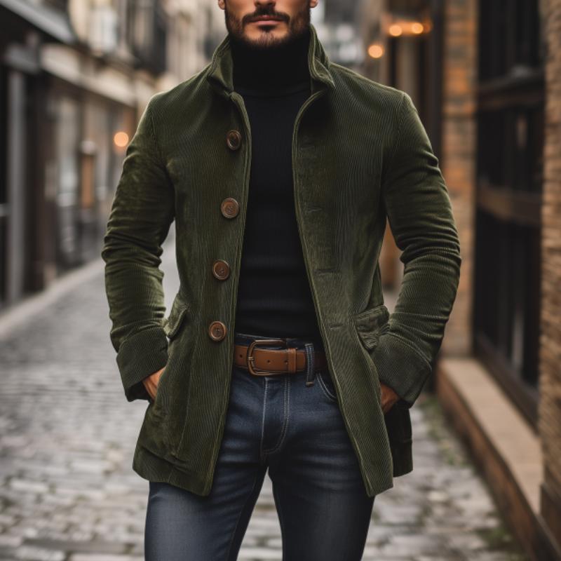 Uomo con cappotto verde in velluto a coste, maglione nero e jeans, cammina in una strada di città. Moda maschile autunnale, stile urbano elegante.
