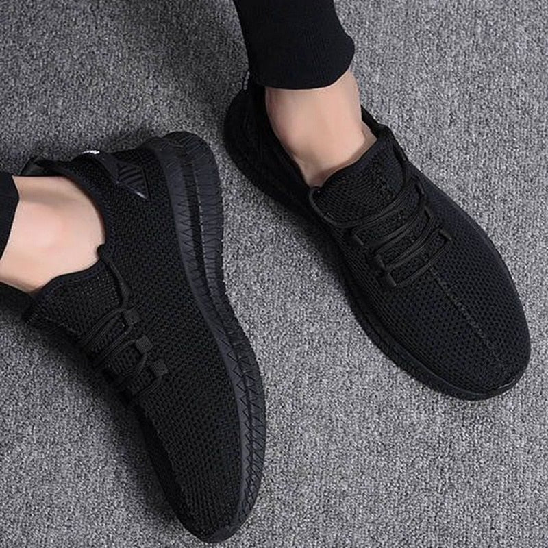 Scarpe da ginnastica nere su sfondo grigio, design moderno e traspirante, perfette per sport e tempo libero. Calzature comode e alla moda.