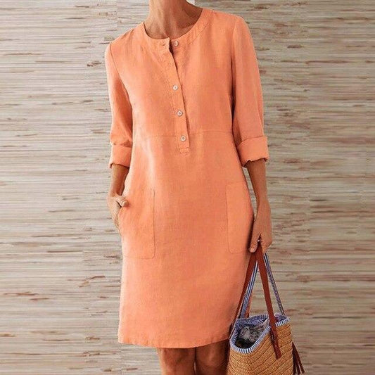 Donna con abito di lino arancione, maniche lunghe, tasche frontali, tiene una borsa di paglia. Moda estiva casual, abbigliamento femminile elegante.