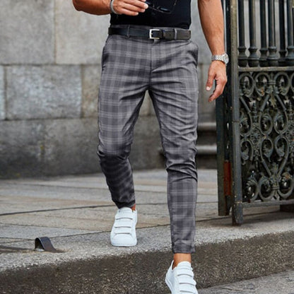 Uomo con pantaloni a quadri grigi e scarpe bianche cammina su marciapiede. Moda maschile elegante, look casual urbano.