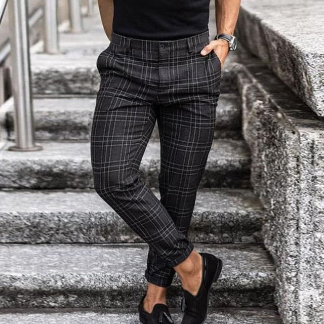 Pantaloni a quadri grigi da uomo, eleganti e moderni, indossati con mocassini neri su una scalinata di pietra. Moda maschile autunnale.