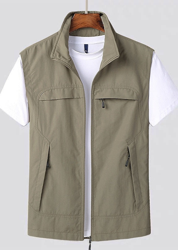 Gilet verde oliva da uomo con cerniera, tasche frontali, indossato sopra una maglietta bianca. Abbigliamento casual, moda maschile.