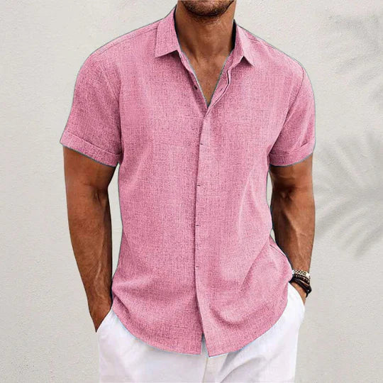 Camicia uomo rosa a maniche corte, tessuto leggero, abbinata a pantaloni bianchi. Moda estiva casual, stile elegante e fresco.