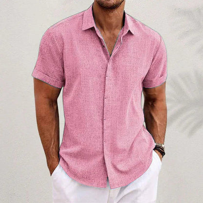 Camicia uomo rosa a maniche corte, tessuto leggero, abbinata a pantaloni bianchi. Moda estiva casual, stile elegante e fresco.