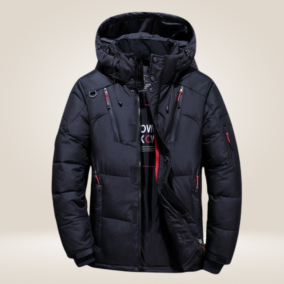 Giacca invernale nera imbottita con cappuccio, cerniera frontale, tasche multiple e dettagli rossi. Ideale per climi freddi e attività all'aperto.