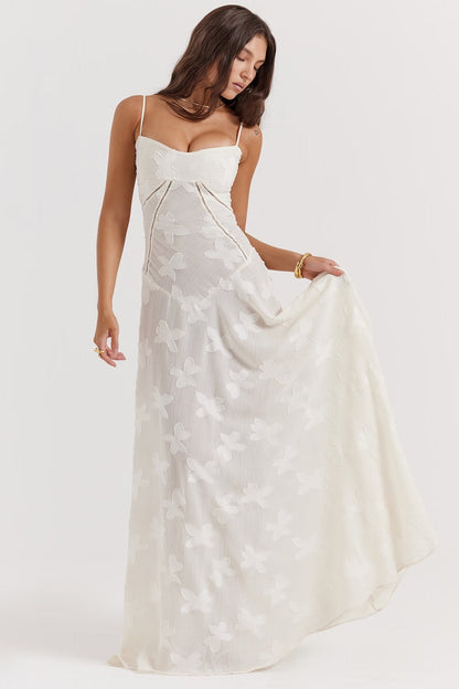 Donna in abito lungo bianco con motivo floreale, spalline sottili, scollo a cuore. Moda elegante, abbigliamento estivo, stile femminile.