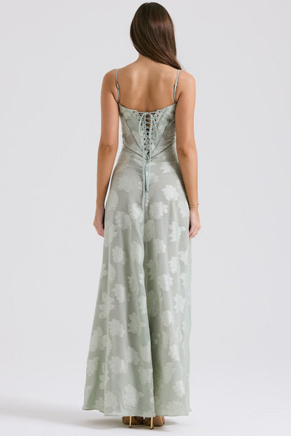 Donna in abito lungo verde chiaro con spalline sottili e motivo floreale, vista posteriore. Elegante vestito estivo, moda femminile.