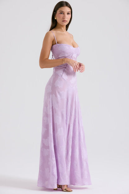 Donna in abito lungo lilla con spalline sottili, design floreale, posa elegante. Moda femminile, abbigliamento estivo, tendenza 2023.