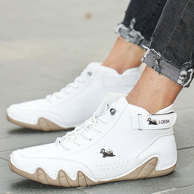 Scarpe da ginnastica bianche alte, design moderno, suola beige, indossate con jeans strappati. Scarpe sportive eleganti per uomo.