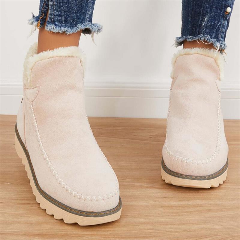Stivaletti beige in pelle scamosciata con fodera in pelliccia sintetica, suola in gomma antiscivolo, indossati con jeans strappati.