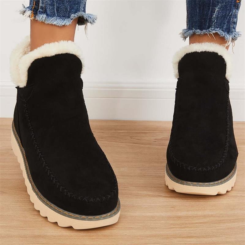 Stivaletti neri in pelle scamosciata con fodera in pelliccia sintetica, suola in gomma beige, indossati con jeans strappati.