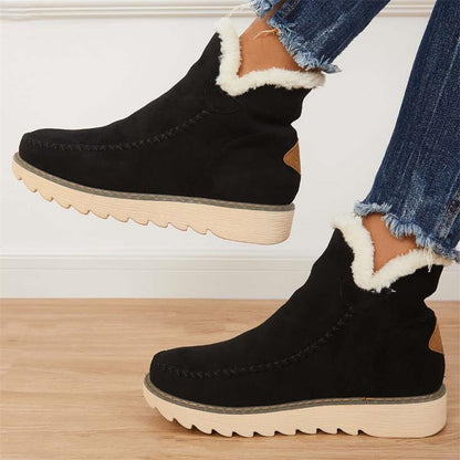 Stivaletti neri invernali con fodera in pelliccia sintetica bianca, suola in gomma beige, indossati con jeans strappati. Moda calzature donna.