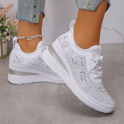 Scarpe da ginnastica bianche con zeppa, dettagli in strass, suola spessa, indossate con jeans strappati. Eleganti e alla moda per look casual.