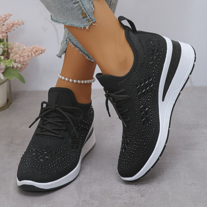 Scarpe da ginnastica nere con zeppa, dettagli in tessuto traspirante, indossate con jeans strappati. Scarpe moda donna, comode e trendy.