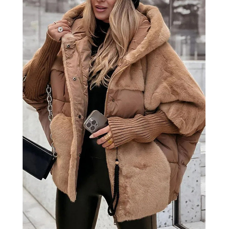 Donna con cappotto invernale marrone, cappuccio e dettagli in pelliccia sintetica, tiene uno smartphone e una borsa nera. Moda autunno-inverno elegante.