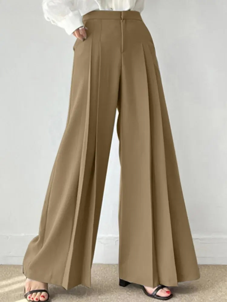 Pantaloni palazzo beige eleganti, vita alta, con pieghe, indossati con sandali neri. Moda donna, abbigliamento casual chic.