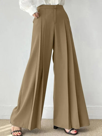 Pantaloni palazzo beige eleganti, vita alta, con pieghe, indossati con sandali neri. Moda donna, abbigliamento casual chic.