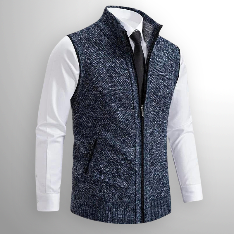 Gilet uomo elegante in maglia blu, con zip frontale, indossato su camicia bianca e cravatta nera. Moda maschile, abbigliamento casual chic.