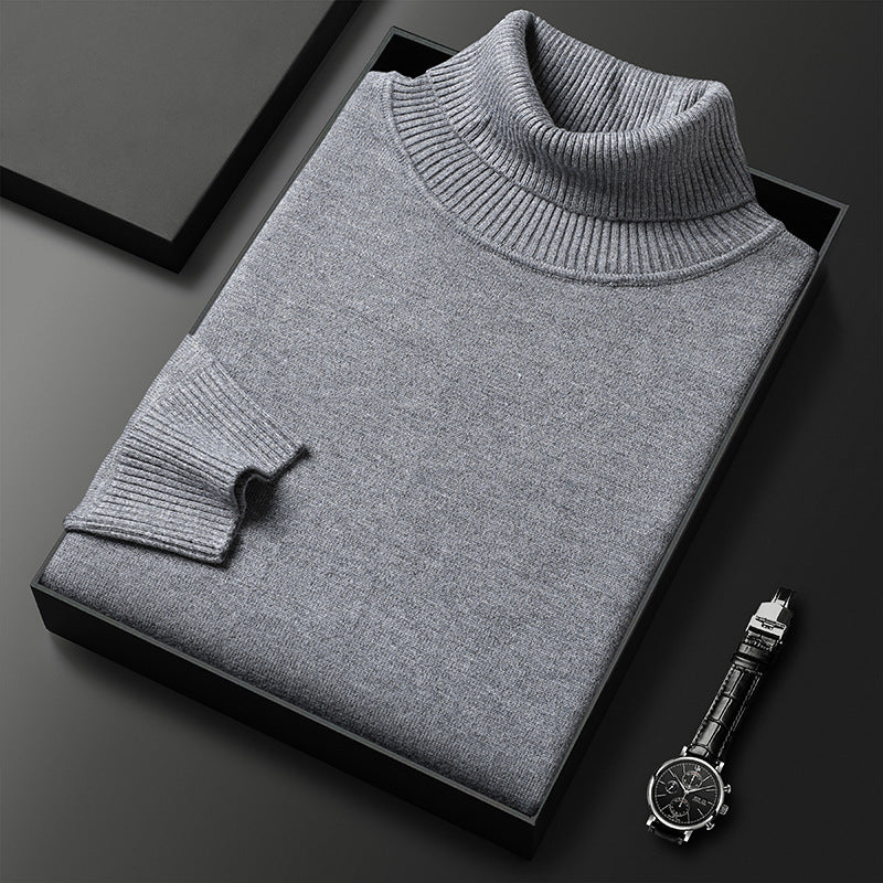 Maglione dolcevita grigio piegato in scatola nera su sfondo scuro, accanto a orologio elegante. Moda uomo, abbigliamento invernale, stile classico.