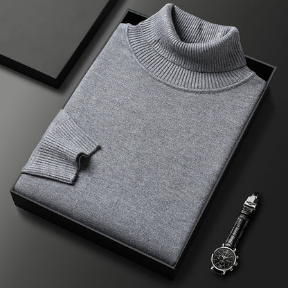 Maglione dolcevita grigio piegato in scatola nera su sfondo scuro, accanto a orologio elegante. Moda uomo, abbigliamento invernale, stile classico.