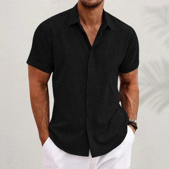 Camicia nera a maniche corte da uomo, stile casual estivo, abbinata a pantaloni bianchi. Look elegante e moderno per la moda maschile.